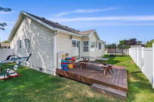 Back of house with a trampoline and a wooden deck