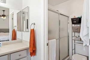 Bathroom with ceiling fan, a stall shower, and vanity