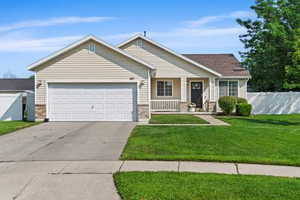 Single story home with an attached garage, driveway, and covered porch