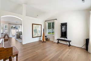 Spare room featuring lofted ceiling, light wood-style flooring, arched walkways, and baseboards