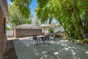 View of patio with outdoor dining area, a fenced backyard, and garage