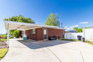 Back of house featuring concrete driveway, brick siding, a gate, and fence