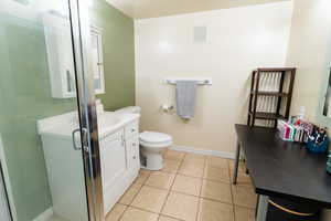 Bathroom featuring vanity, tile patterned floors, a stall shower, toilet, and baseboards