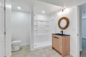 Full bath with toilet, a walk in shower, baseboards, vanity, and recessed lighting