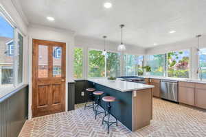 Kitchen featuring dishwasher, brick floors, a sink, a textured ceiling, and light countertops