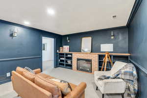 Carpeted living area featuring ornamental molding, a brick fireplace, and wainscoting