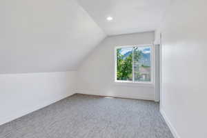 Additional living space featuring lofted ceiling, baseboards, and carpet