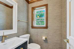 Half bathroom with tile walls, toilet, and vanity