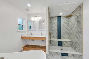 Primary bathroom featuring a freestanding bath, a marble finish shower, marble look tile flooring, and recessed lighting