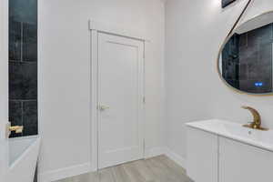 Full bathroom with a bath, vanity, tiled shower, and baseboards