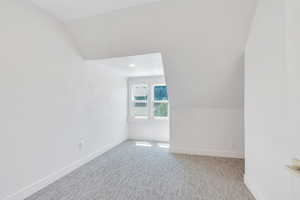 Additional living space with baseboards, carpet, and vaulted ceiling