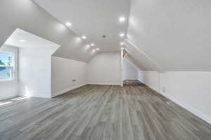 Additional living space with light wood-style floors, recessed lighting, baseboards, and lofted ceiling