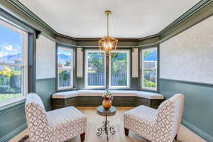 Living area featuring a chandelier, wood finished floors, plenty of natural light, and ornamental molding