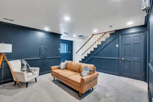 Carpeted living room featuring stairs, recessed lighting, and ornamental molding
