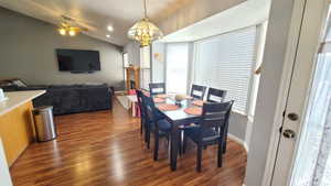 Dining space with wood finished floors, lofted ceiling, a chandelier, ceiling fan, and baseboards