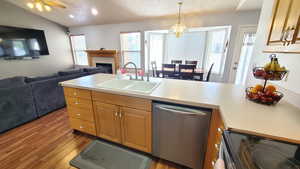 Kitchen featuring a sink, electric range, dishwasher, open floor plan, and wood finished floors