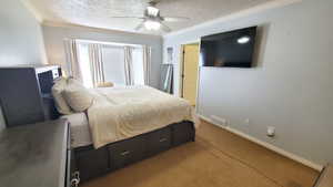 Bedroom featuring light colored carpet, baseboards, ceiling fan, ornamental molding, and a textured ceiling