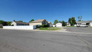 View of front of house with a residential view, fence, a garage, and stucco siding