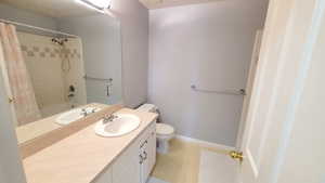 Bathroom with toilet, vanity, and baseboards