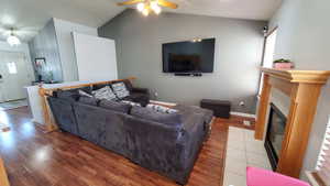 Living room with vaulted ceiling, wood-style flooring, ceiling fan, healthy amount of natural light, and a fireplace