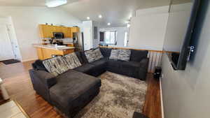 Living room with vaulted ceiling, light wood-style flooring, and baseboards