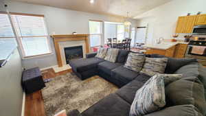 Living area with light wood finished floors, vaulted ceiling, plenty of natural light, baseboards, and a tile fireplace