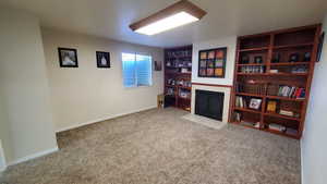 Living room with carpet floors, a tile fireplace, and baseboards