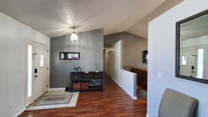 Foyer entrance featuring wood finished floors, lofted ceiling, and baseboards