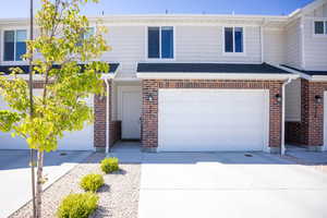 Townhome / multi-family property with brick siding, concrete driveway, an attached garage, and a shingled roof
