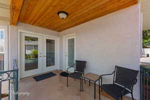 View of exterior entry with french doors, stucco siding, and a patio