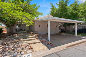 View of front of home featuring stucco siding, an attached carport, a tiled roof, and covered porch