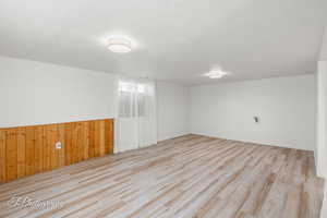 Unfurnished room with wood finished floors, wood walls, wainscoting, and baseboards