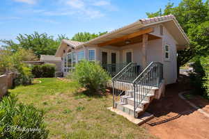 Back of property with stucco siding, a yard, a tile roof, and cooling unit
