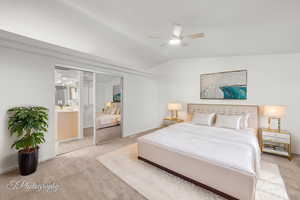 Bedroom featuring light carpet, vaulted ceiling, baseboards, and ensuite bath