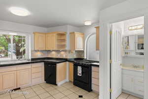 Kitchen with light brown cabinetry, black appliances, a sink, and tasteful backsplash