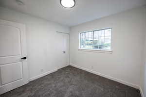 Unfurnished bedroom with dark colored carpet, baseboards, and a closet