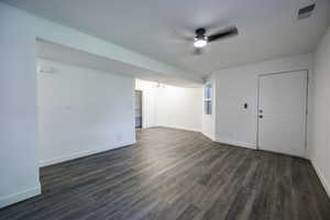 Empty room with ceiling fan, baseboards, and dark wood-type flooring