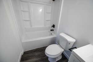 Full bath with wood finished floors, toilet, shower / washtub combination, baseboards, and vanity