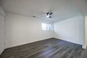 Unfurnished room featuring a ceiling fan, dark wood-type flooring, and baseboards