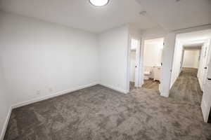 Unfurnished bedroom with carpet floors, baseboards, and ensuite bath