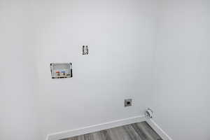 Laundry area featuring hookup for a washing machine, hookup for an electric dryer, baseboards, and wood finished floors