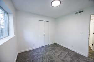 Unfurnished bedroom with baseboards, dark carpet, and a closet
