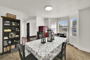 Dining space with crown molding, baseboards, and dark carpet