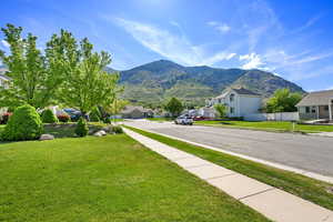 View of asphalt road featuring a residential view, sidewalks, a mountain view, and curbs