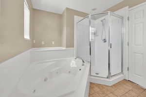 Master bathroom with a jetted tub, a shower stall, and tile patterned flooring