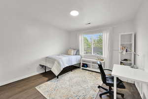 Bedroom with wood finished floors, a desk, and baseboards