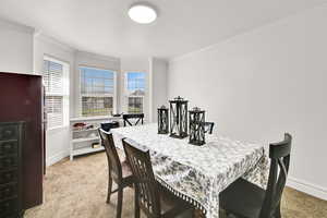 Separate dining space featuring crown molding, light colored carpet, and baseboards