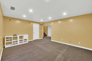 Basement family room with stairs, dark carpet, baseboards, and recessed lighting