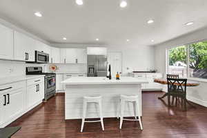 Kitchen with appliances with stainless steel finishes, tasteful backsplash, a breakfast bar area, a kitchen island, and recessed lighting