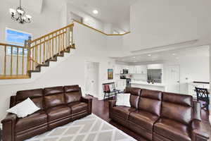 Living area with wood finished floors, a chandelier, a towering ceiling, baseboards, and stairway
